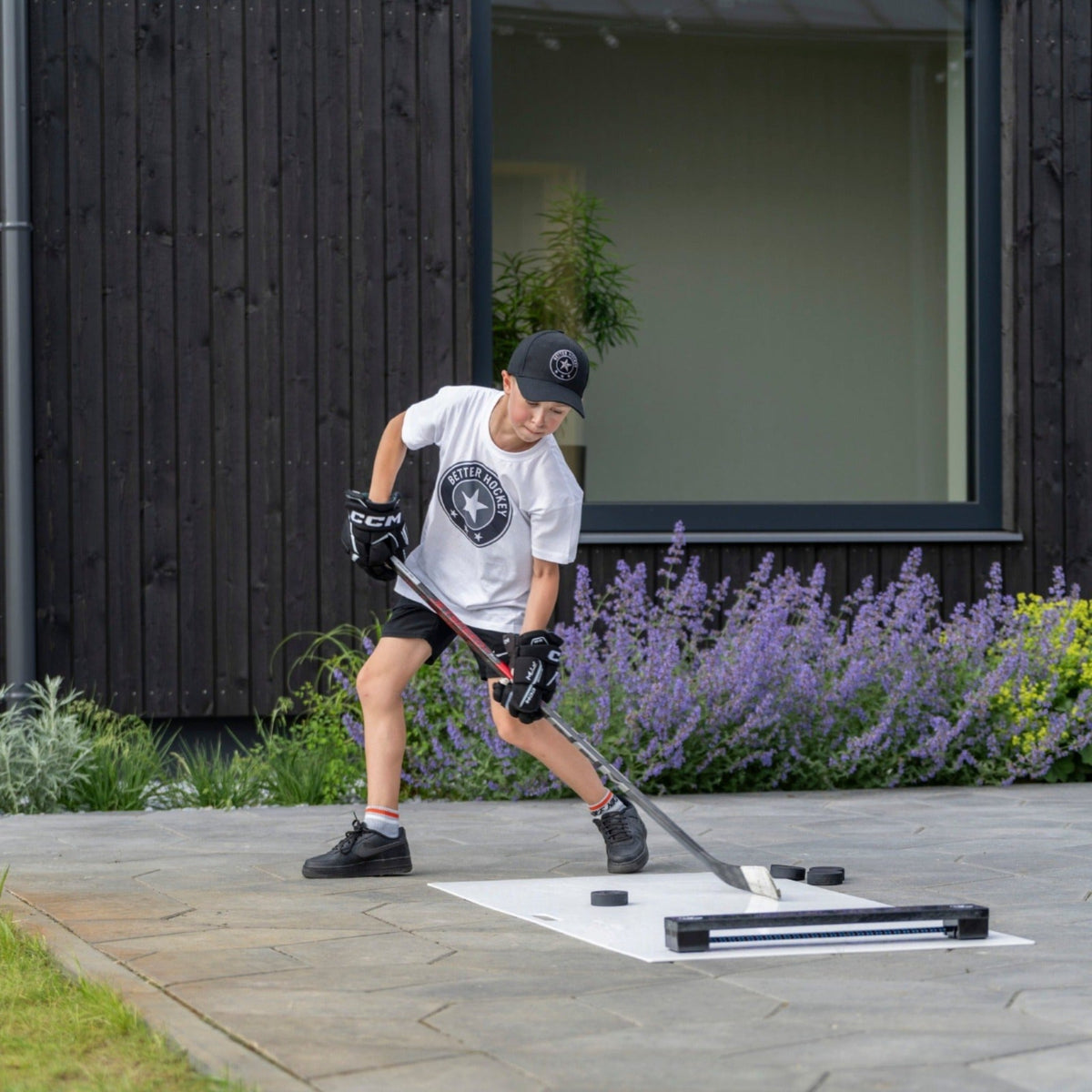 Young hockey player practicing passing against a rebounder in a backyard driveway setting